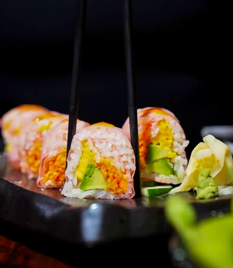 Rolls served in a dark bowl with chopsticks resting across it
