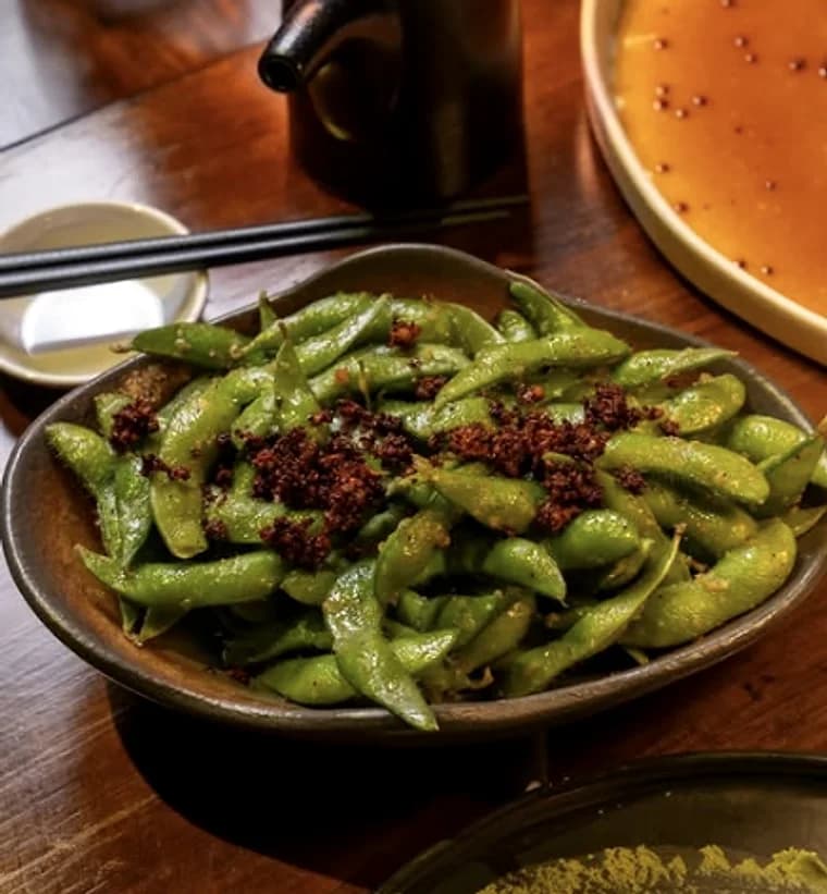 A bowl of chilli-dusted edamame on a wooden table