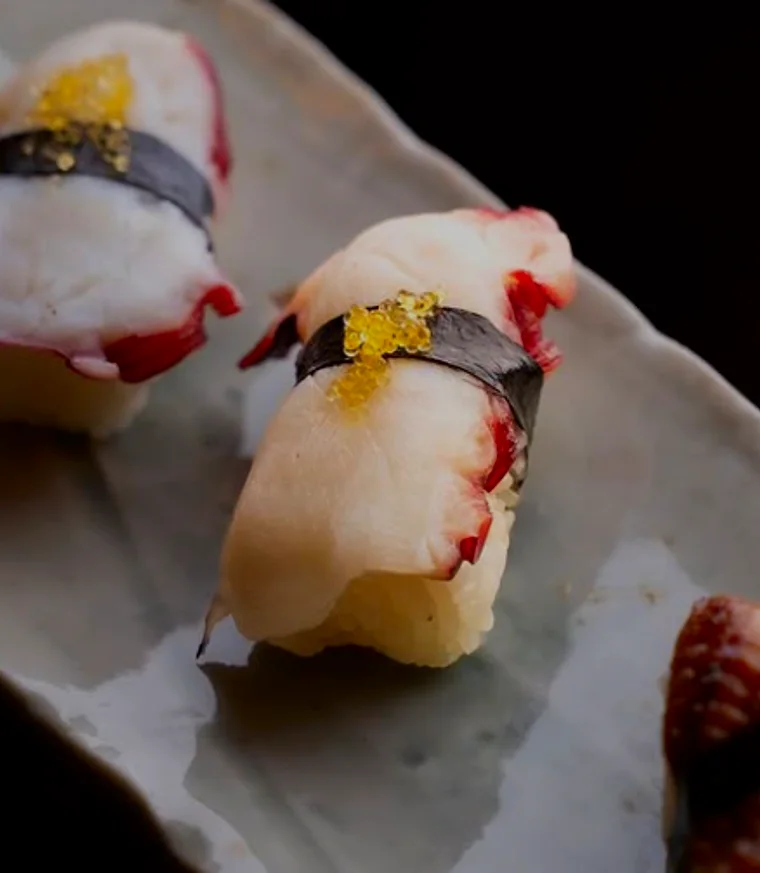 Nigiri topped with gold leaf on a marble counter