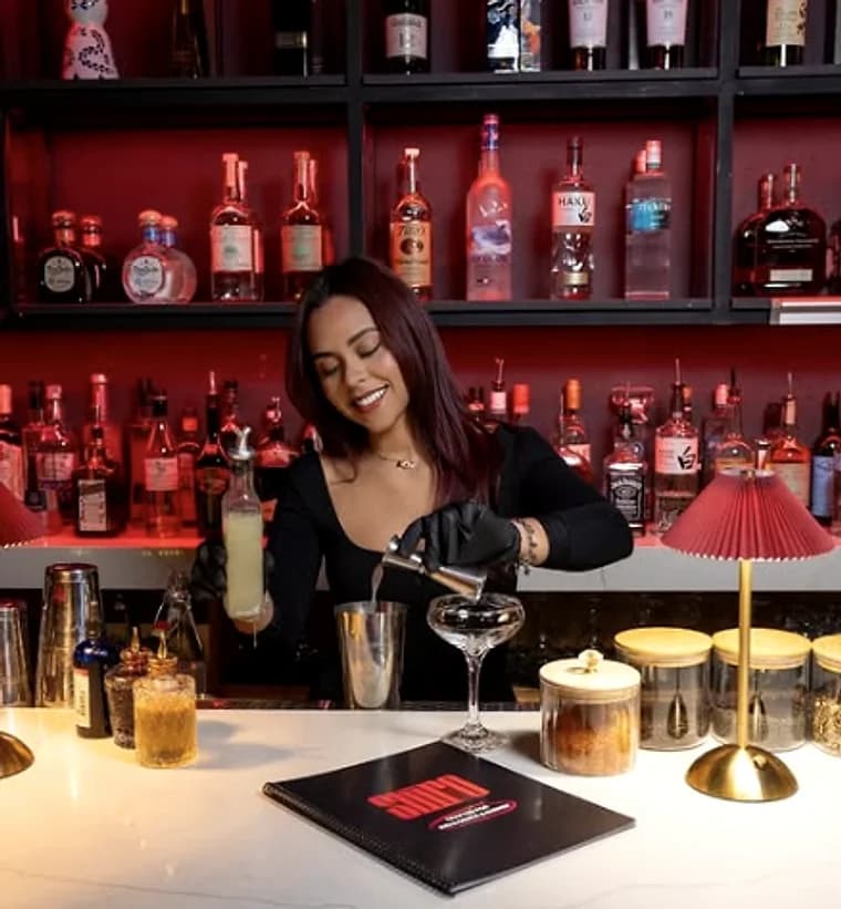 A bartender working in front of the red-lit bottle wall
